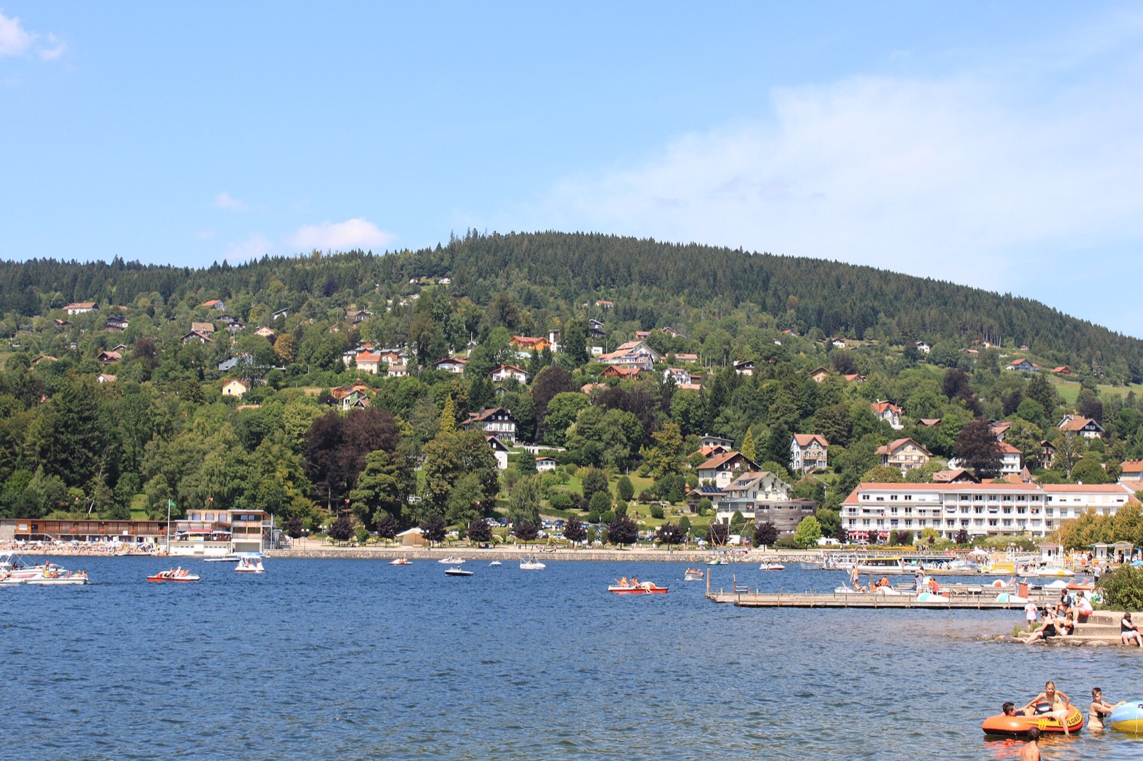 Le lac de Gérardmer en août, rive boisée et maisons au bord de l'eau